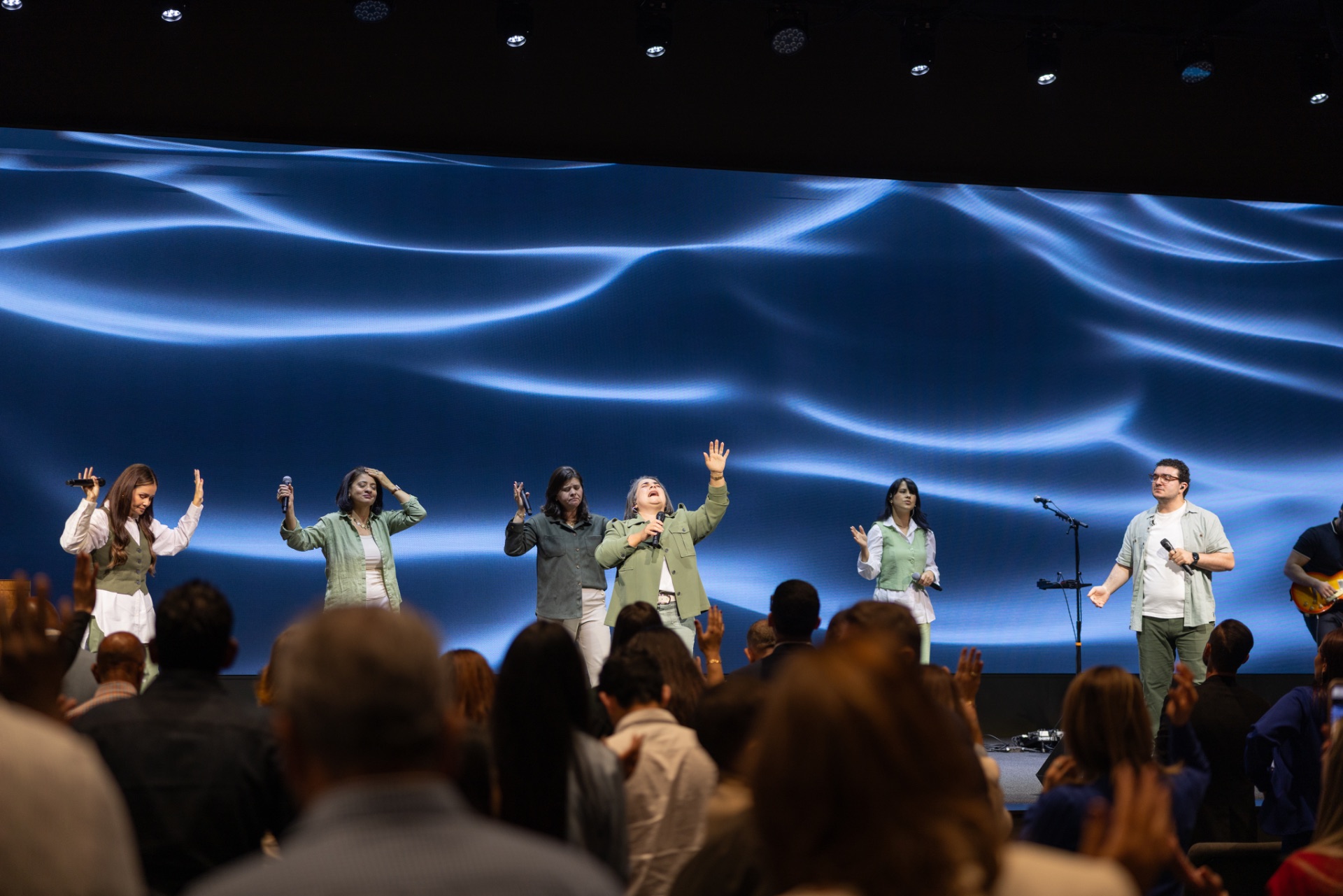 Worship team leading at Reach Church in Hyannis, MA, in front of a large blue LED video wall installed by AES Integration, with the congregation standing